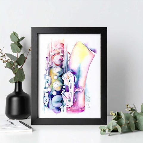 Framed artwork of a colorful saxophone on a white surface with greenery.