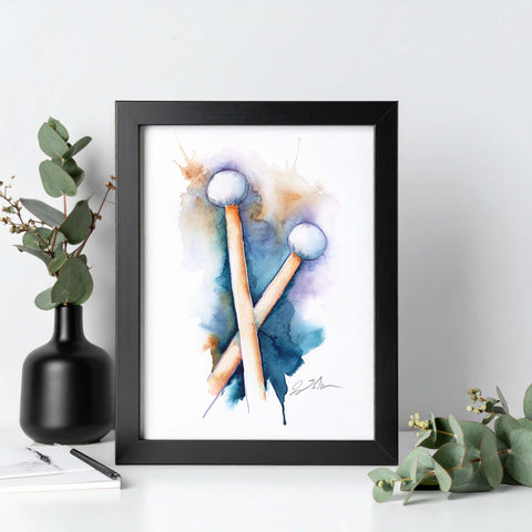 Framed artwork of drumsticks with watercolor design on a white surface with decorative elements.