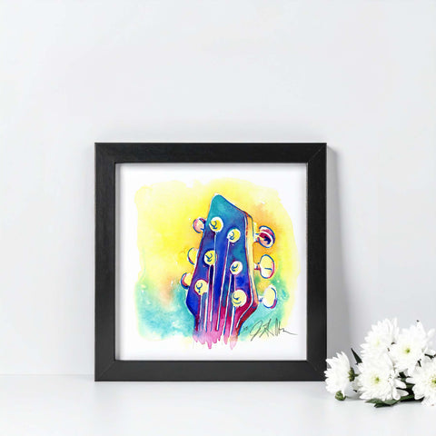 Framed colorful abstract art piece on a white wall with flowers in the corner.