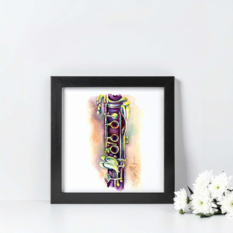 Framed artwork with a colorful clarinet on a white surface with flowers.