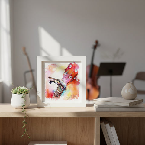 Framed watercolor painting of a guitar headstock on a wooden desk with a blurred background
