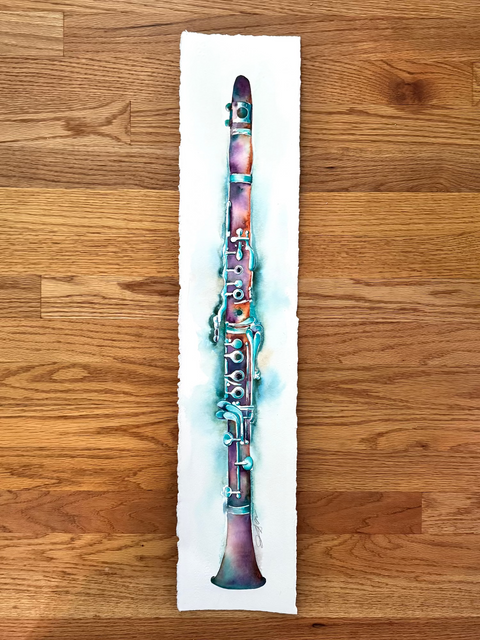 Colorful clarinet on a white rectangular card against a wooden background
