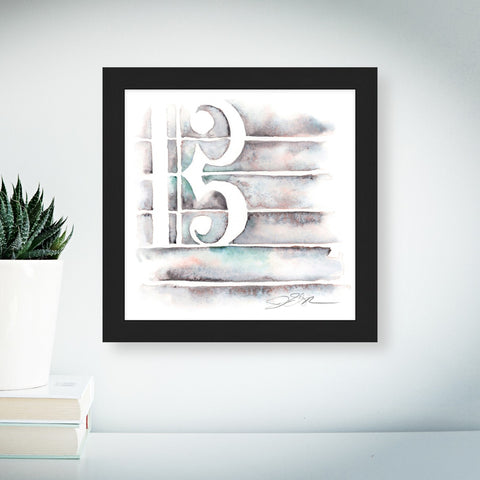 Framed abstract musical symbol art piece on a wall with a plant and books in the foreground.