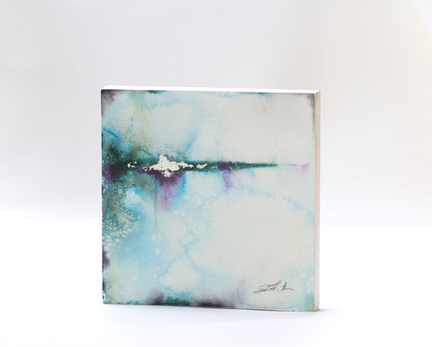 A watercolor painting featuring a blend of blue and green colors with silver leaf accents, signed by the artist.