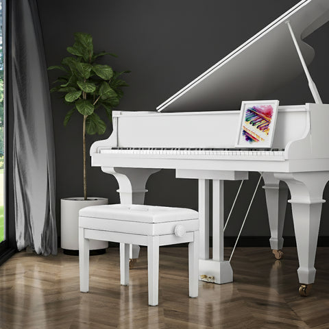 White grand piano with a panting in a modern room with a plant and window.