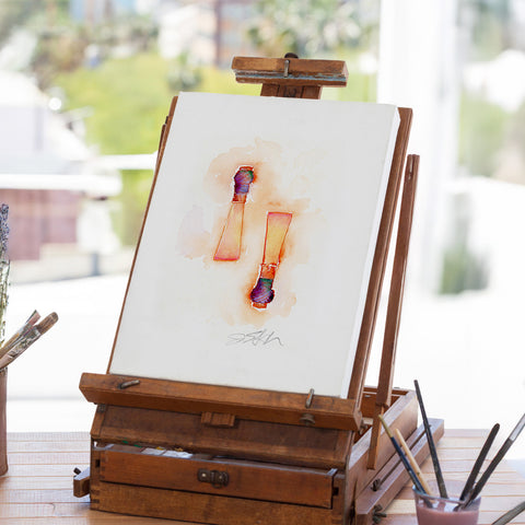 Art easel with a watercolor painting of two reeds on a blurred outdoor background