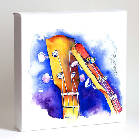 A framed painting of two ukulele headstocks in vibrant blue, yellow, and orange hues on a white background.