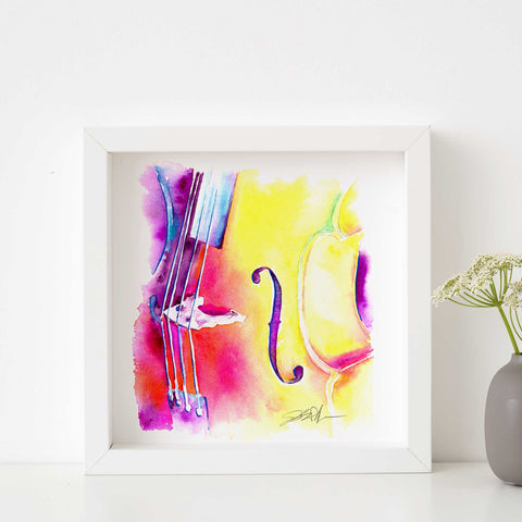 A framed watercolor painting of a cello with vibrant pink and yellow colors on a white background, with a signature at the bottom.