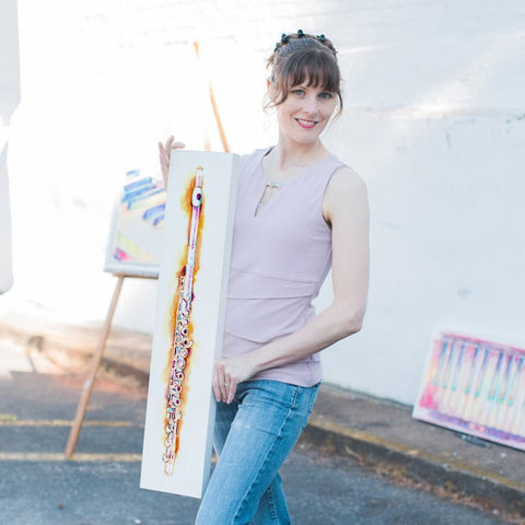 an artist holding a painting of a brightly colored painting