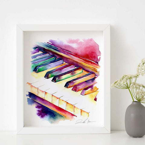 A framed watercolor painting of colorful piano keys by Jamie Hansen, displayed on a white shelf with a vase of flowers in the background.