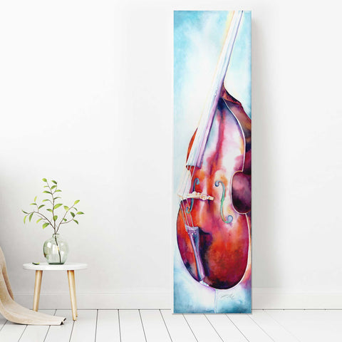 A tall, vertical canvas print of an upright bass placed against a light-colored wall, with a small plant and table to the side.