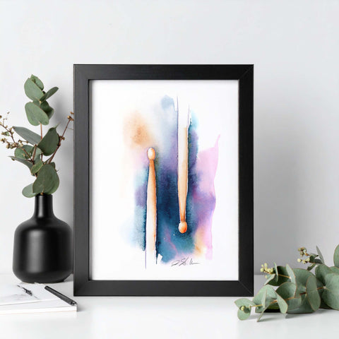 Framed abstract art print percussion drumsticks with colorful brush strokes on a white wall.