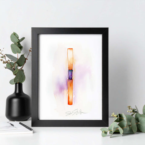 Framed abstract art piece on a white surface with a black frame, surrounded by greenery.