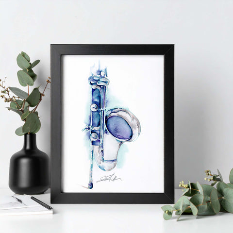 Framed artwork of a blue and white musical instrument on a white surface with greenery.