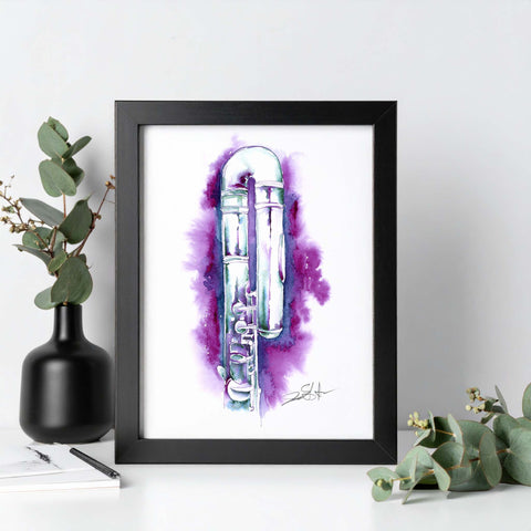 Framed artwork of a flute with watercolor design on a white surface with greenery.
