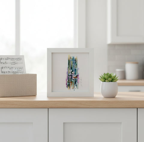 Framed abstract art on a kitchen counter with a plant and music sheet box.