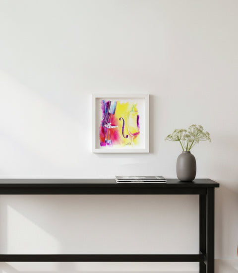 Framed abstract art on a wall above a black console table with a vase and plant.