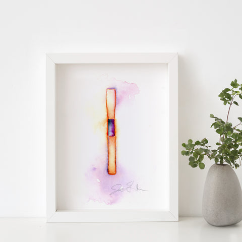 Framed abstract reed artwork with a plant on a white surface