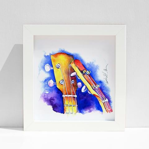 A framed painting of two ukulele headstocks in vibrant blue, yellow, and orange hues on a white background.